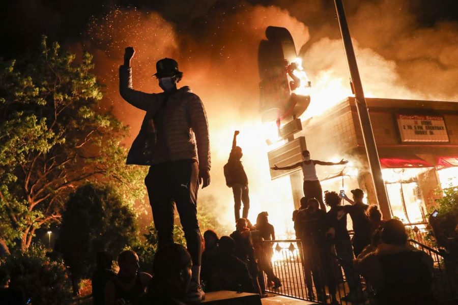 Protesters standing beside a burning restaurant. 